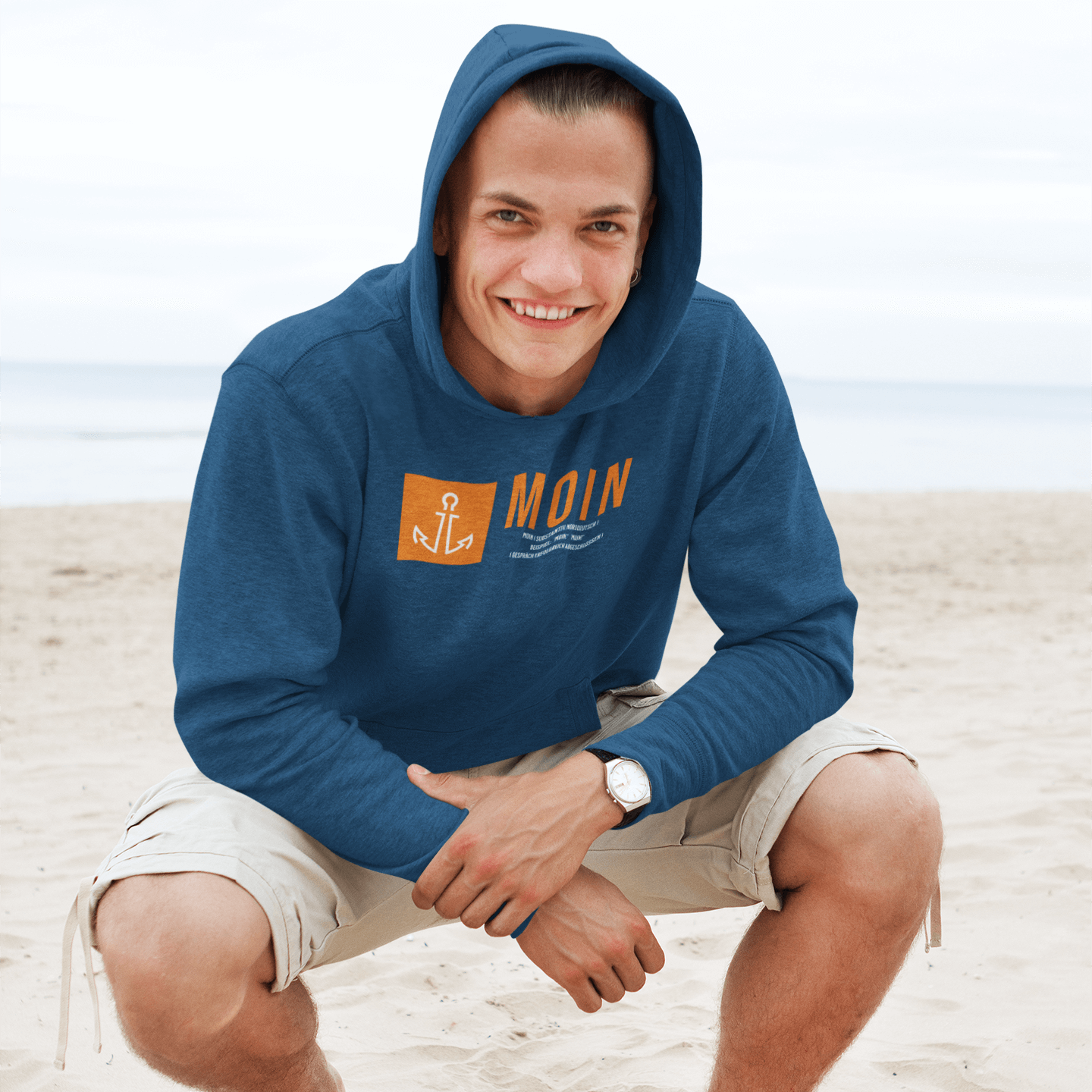 junger mann am strand trägt maritime mode herren mit einem Anker Motiv und dem Schriftzug Moin